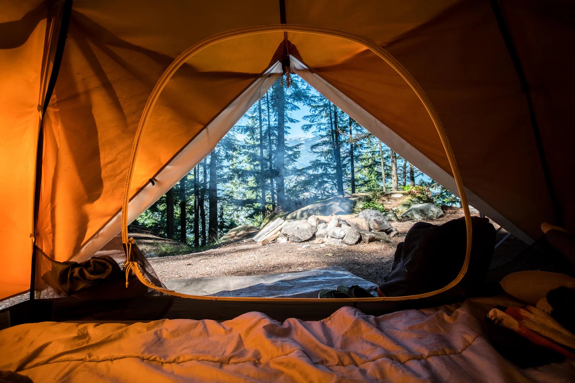 Tent pitched at dusk beneath a mountain skyline